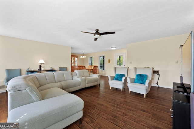 living room featuring ceiling fan with notable chandelier and dark wood-type flooring