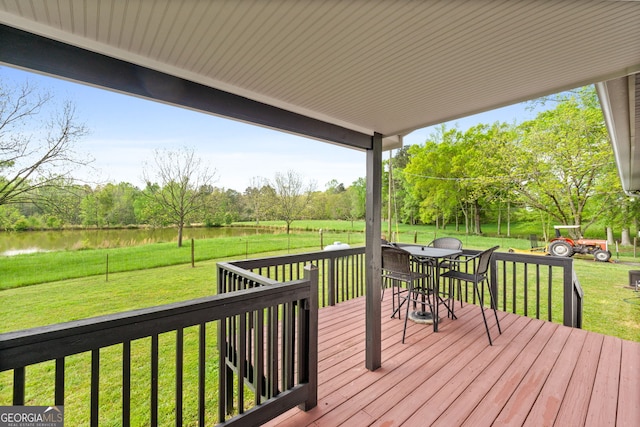 wooden terrace featuring a water view and a lawn