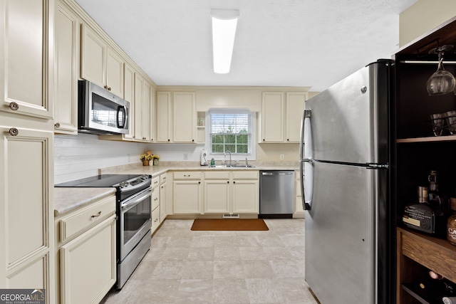 kitchen featuring appliances with stainless steel finishes, sink, and cream cabinets