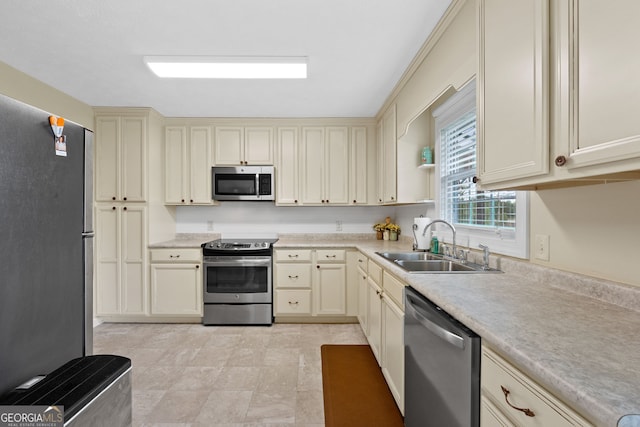 kitchen with sink, cream cabinetry, and appliances with stainless steel finishes