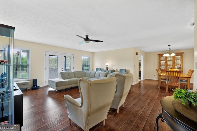 living room featuring dark wood-type flooring, ceiling fan with notable chandelier, a textured ceiling, and french doors