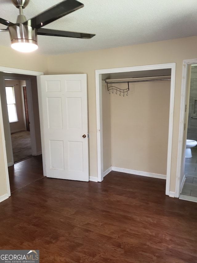 unfurnished bedroom with ceiling fan, a textured ceiling, dark hardwood / wood-style floors, a closet, and ensuite bath