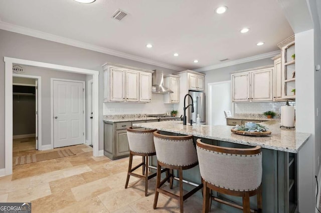 kitchen with stainless steel fridge, tasteful backsplash, light stone countertops, a kitchen bar, and wall chimney exhaust hood