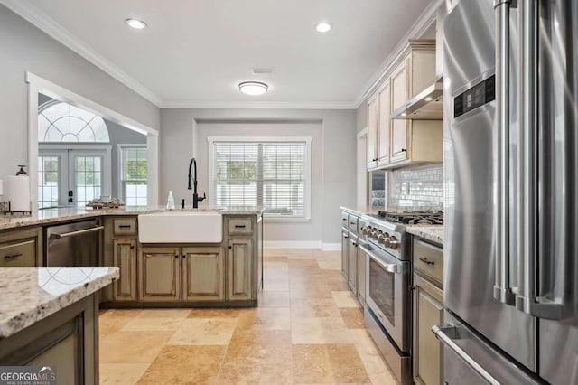 kitchen featuring backsplash, high end appliances, sink, crown molding, and light stone counters