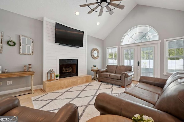 living room featuring ceiling fan, high vaulted ceiling, a large fireplace, and plenty of natural light