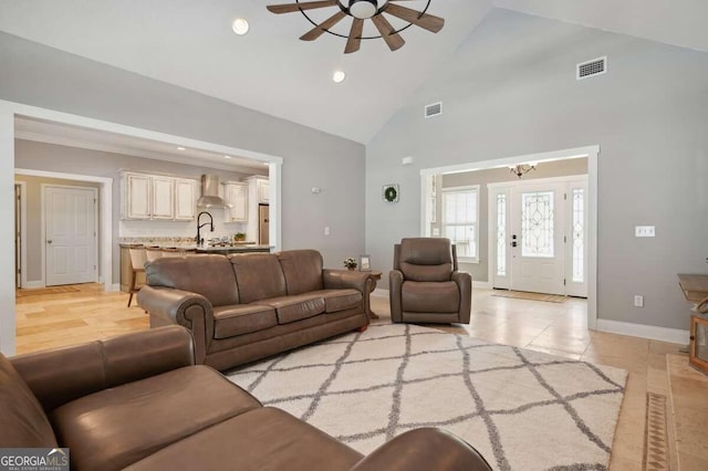 living room with light tile patterned flooring, ceiling fan with notable chandelier, and high vaulted ceiling