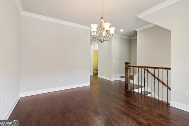 spare room with dark wood-type flooring, crown molding, and an inviting chandelier