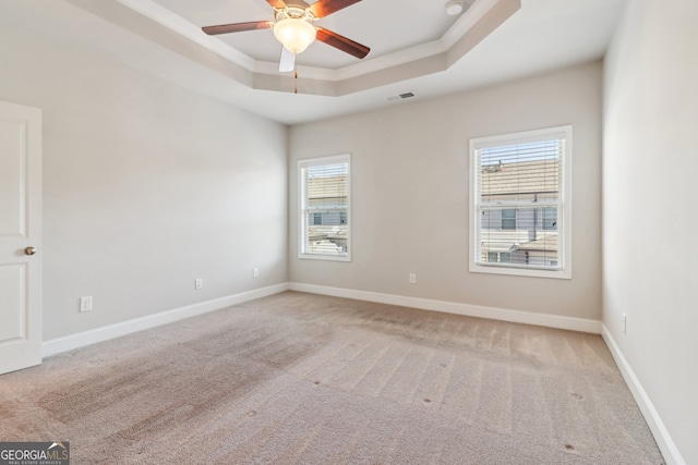 carpeted empty room with a raised ceiling and ceiling fan