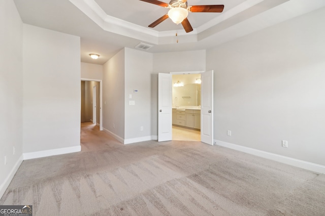 empty room with ceiling fan, a tray ceiling, and light colored carpet