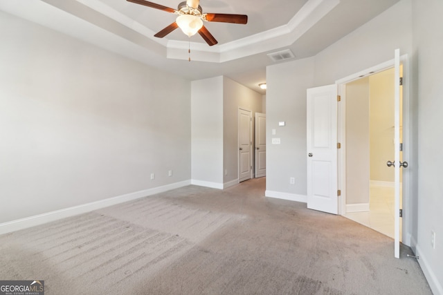 unfurnished bedroom with light carpet, ceiling fan, and a raised ceiling