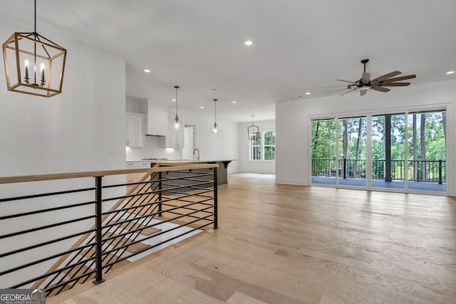 interior space featuring sink, ceiling fan with notable chandelier, and light wood-type flooring