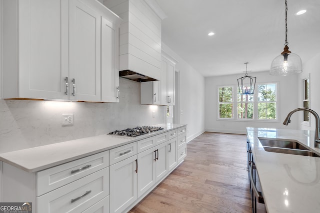 kitchen featuring white cabinets, pendant lighting, stainless steel gas cooktop, sink, and light hardwood / wood-style floors