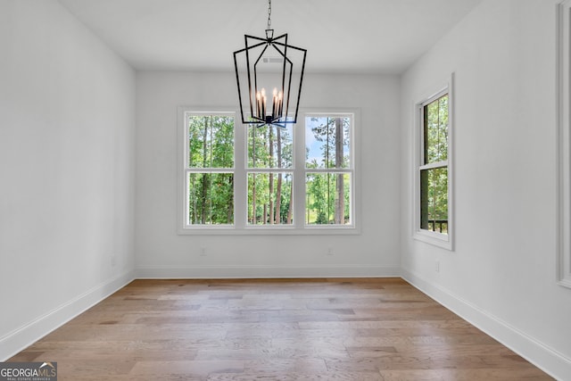 unfurnished dining area featuring a wealth of natural light, a chandelier, and light wood-type flooring