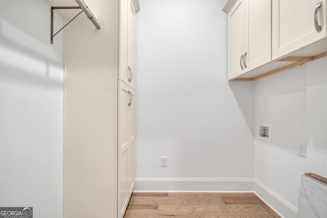 laundry area featuring light hardwood / wood-style floors, washer hookup, and cabinets