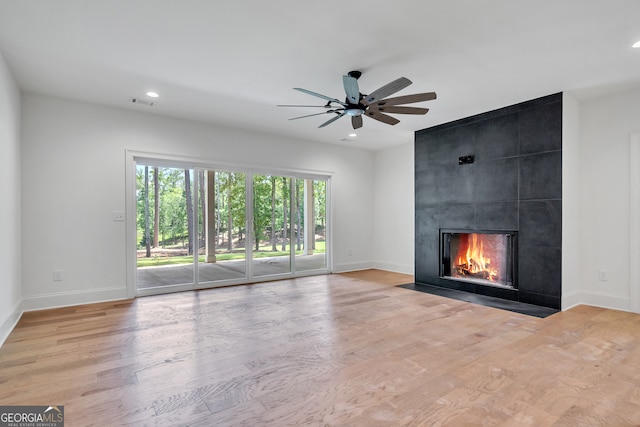 unfurnished living room with light hardwood / wood-style floors, a large fireplace, and ceiling fan