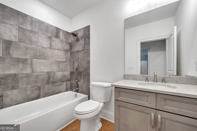 full bathroom featuring vanity, hardwood / wood-style floors, tiled shower / bath combo, and toilet