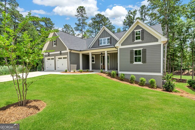 craftsman house featuring a front yard, covered porch, and a garage