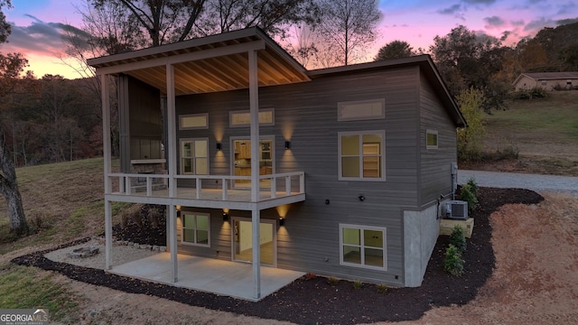 back house at dusk with a patio and cooling unit