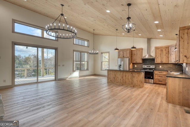 kitchen with a healthy amount of sunlight, appliances with stainless steel finishes, sink, wall chimney exhaust hood, and pendant lighting