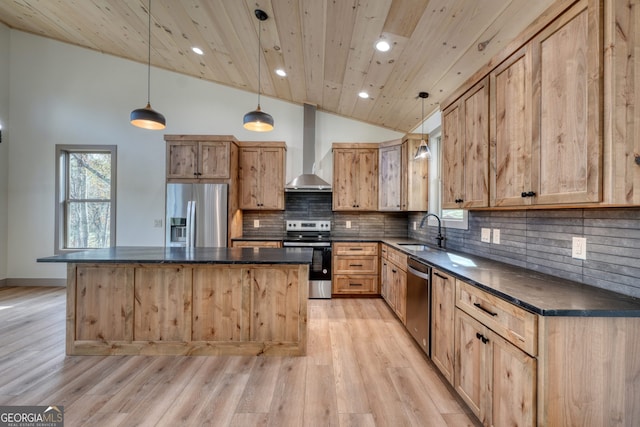 kitchen featuring wall chimney exhaust hood, stainless steel appliances, a center island, decorative light fixtures, and light hardwood / wood-style floors