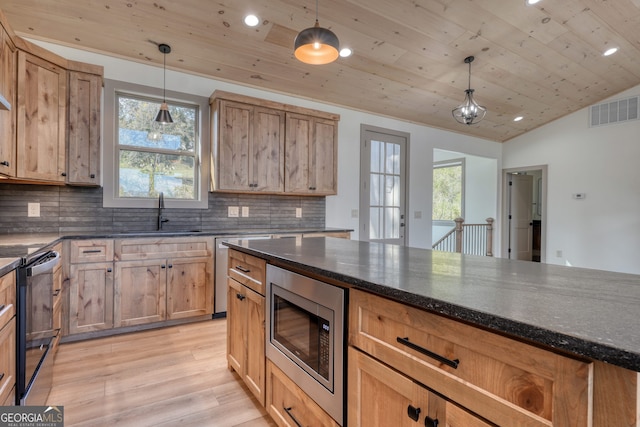 kitchen featuring stainless steel microwave, a healthy amount of sunlight, sink, and hanging light fixtures