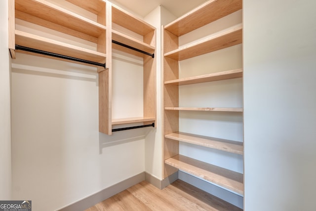 walk in closet with light hardwood / wood-style flooring