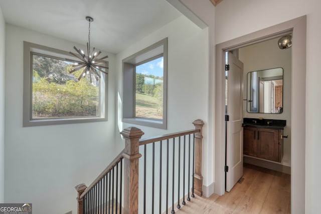 hall with a wealth of natural light, light hardwood / wood-style flooring, and a notable chandelier