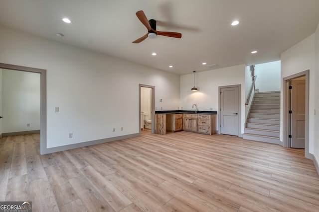 unfurnished living room with light hardwood / wood-style floors, sink, and ceiling fan