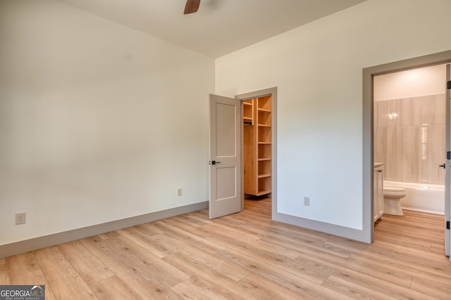 unfurnished bedroom with light hardwood / wood-style flooring, a walk in closet, ensuite bathroom, and ceiling fan