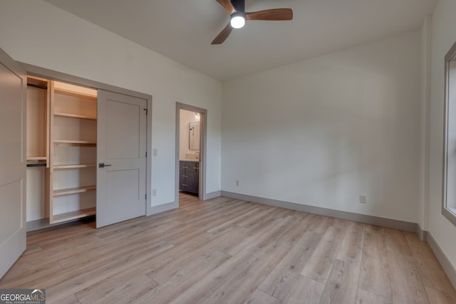 unfurnished bedroom with light hardwood / wood-style floors, a closet, connected bathroom, and ceiling fan