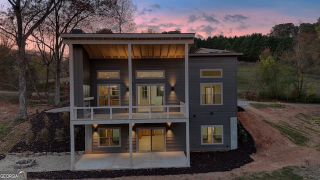 back house at dusk with a balcony and a patio