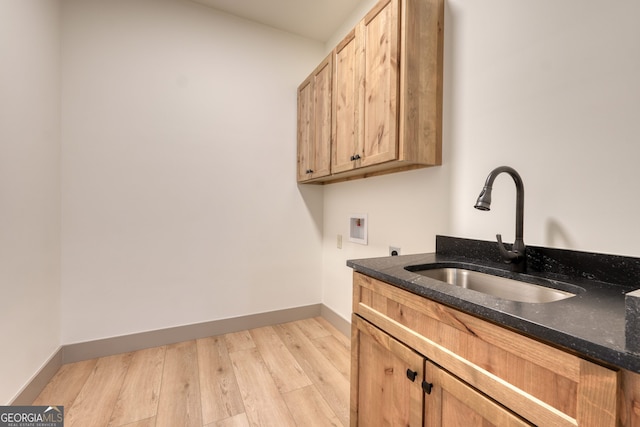 laundry area with hookup for a washing machine, sink, light hardwood / wood-style floors, electric dryer hookup, and cabinets