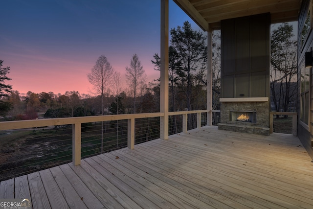 deck at dusk with an outdoor stone fireplace