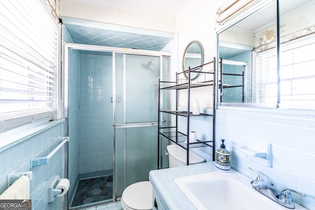 bathroom featuring tile walls, toilet, a shower with shower door, vanity, and crown molding