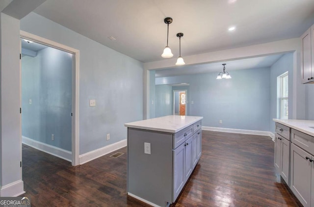 kitchen with gray cabinets, a center island, decorative light fixtures, and dark hardwood / wood-style flooring