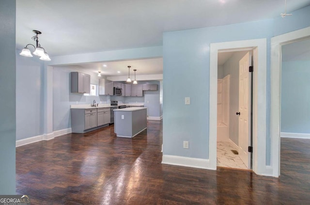 kitchen with dark wood-type flooring, gray cabinetry, sink, a center island, and decorative light fixtures