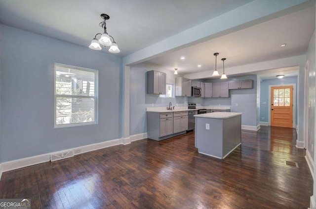 kitchen featuring gray cabinetry, appliances with stainless steel finishes, a kitchen island, dark hardwood / wood-style flooring, and pendant lighting