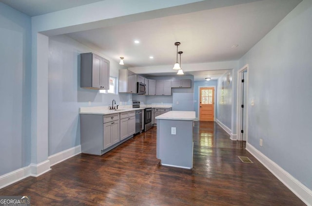 kitchen featuring a healthy amount of sunlight, appliances with stainless steel finishes, a kitchen island, and hanging light fixtures