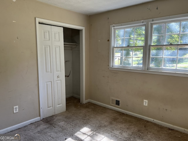 unfurnished bedroom with a textured ceiling and light colored carpet