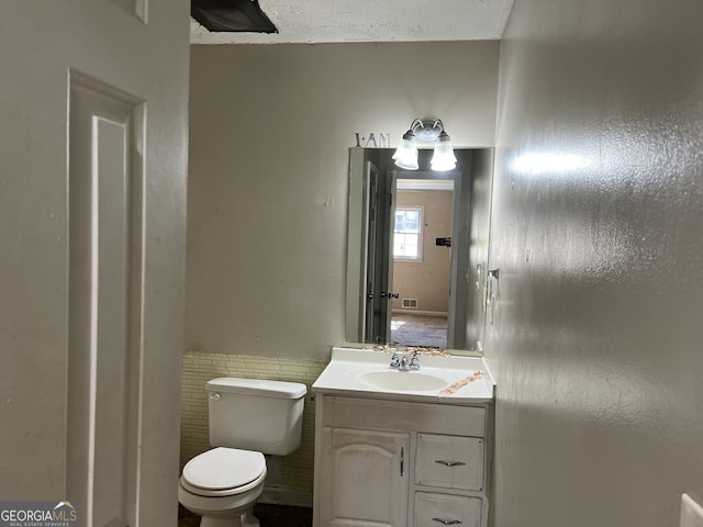 bathroom with vanity, toilet, and tile walls