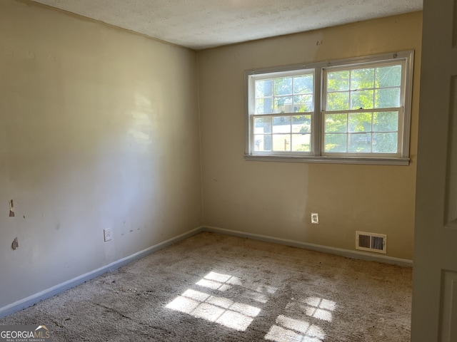 carpeted empty room with a textured ceiling