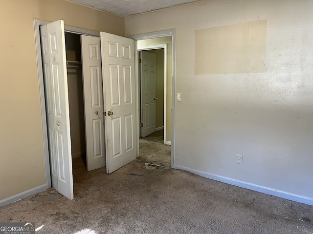 unfurnished bedroom featuring a textured ceiling, light colored carpet, and a closet