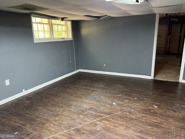 basement featuring a drop ceiling and dark hardwood / wood-style floors