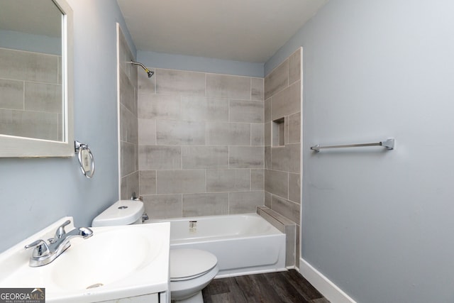 full bathroom featuring vanity, tiled shower / bath combo, hardwood / wood-style flooring, and toilet