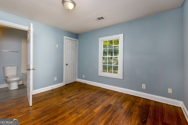 unfurnished bedroom with connected bathroom and dark hardwood / wood-style floors