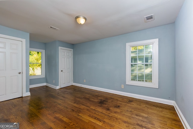 unfurnished bedroom with multiple windows and dark hardwood / wood-style flooring