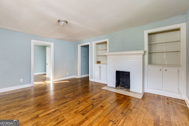 unfurnished living room with built in features, wood-type flooring, and a fireplace