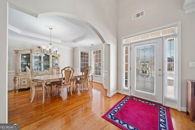 foyer entrance with crown molding, hardwood / wood-style flooring, a chandelier, and a raised ceiling