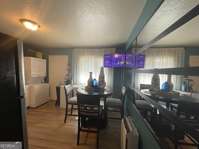 dining room featuring a textured ceiling, stacked washer / drying machine, and wood-type flooring