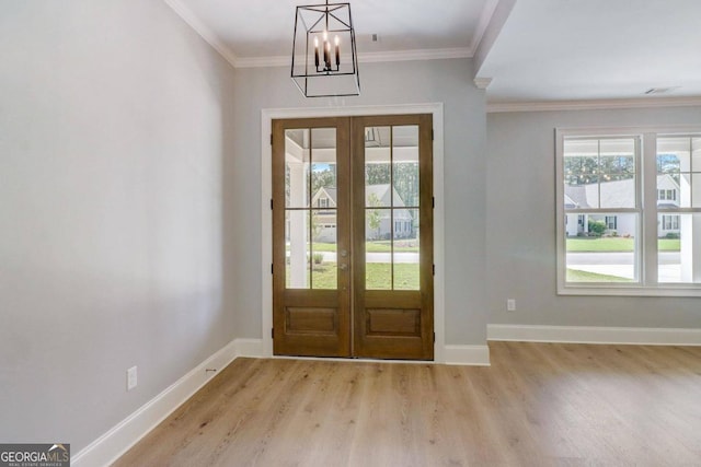 foyer featuring ornamental molding, an inviting chandelier, light wood-type flooring, and french doors